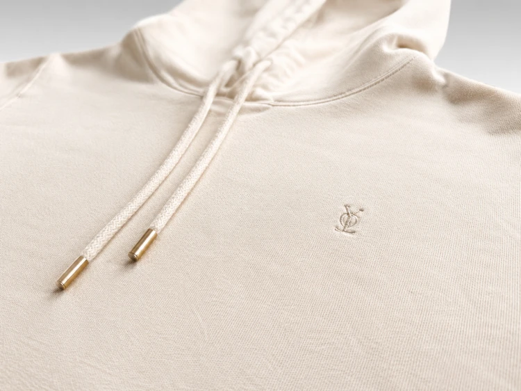 Zbliżenie na haftowane logo oraz wysokiej jakości wykończenie bluzy hoodie premium. Miękka bawełna i dopracowane detale podkreślają minimalistyczny charakter produktu.